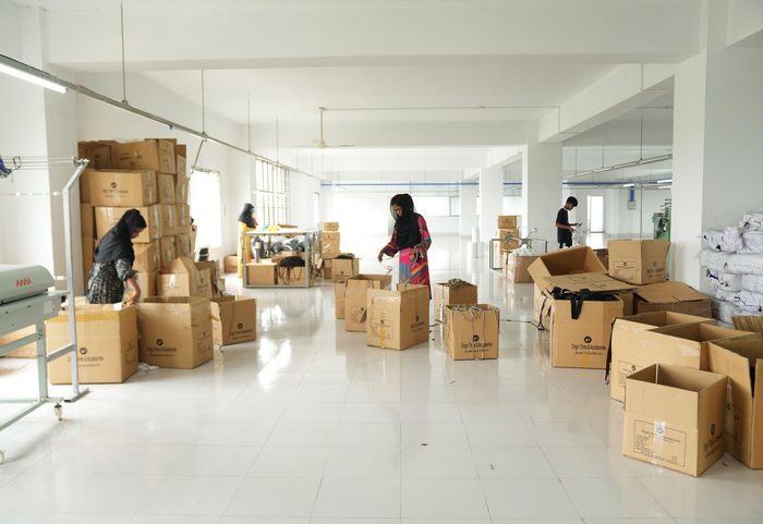 Ware wird am Packtisch aus einem braunen Karton in neue Kartons umgepackt (Illustrationsfoto)